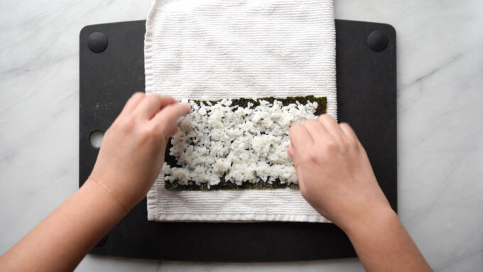 spreading rice evenly on half nori sheet