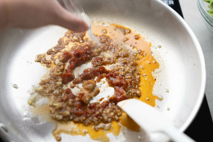 adding sauce for spicy chili garlic edamame