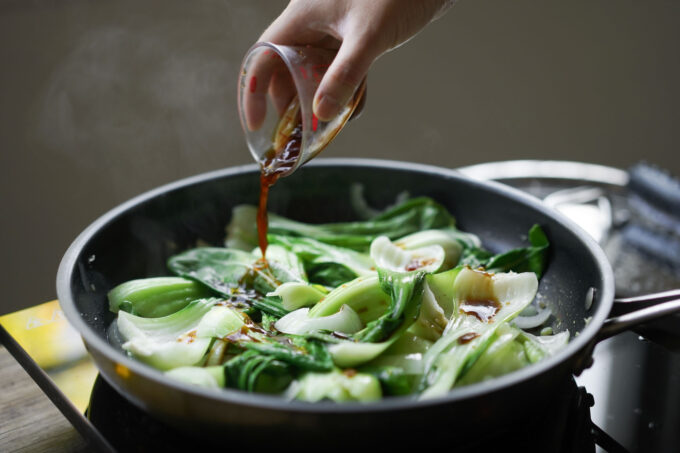 pouring seasoning onto bok choy