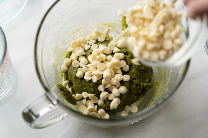 pouring in white chocolate chips into matcha cookie batter