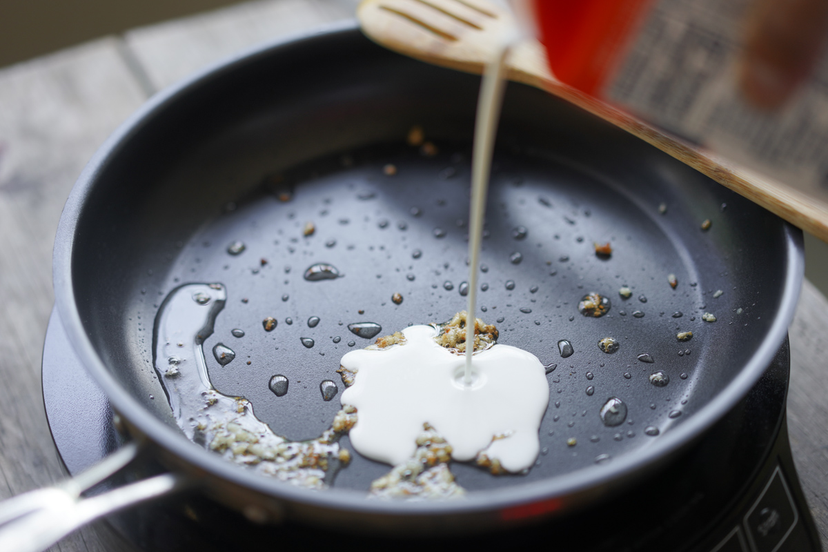 pouring heavy cream into the pan
