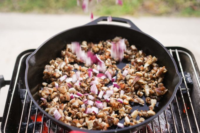 adding onions to cast iron full of sisig