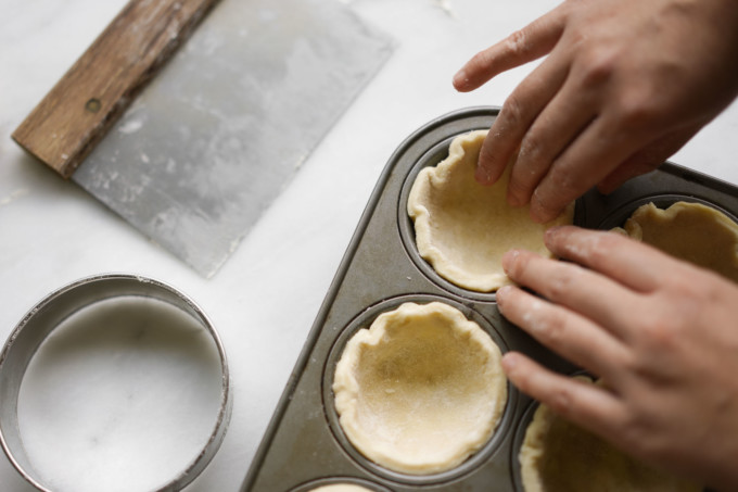 pressing dough rounds into cupcake mold