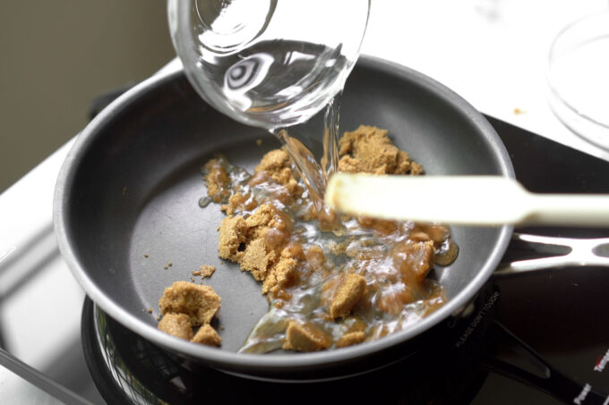 adding water to dark brown sugar in a pan