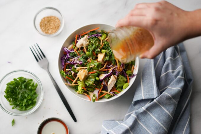 pouring Asian dressing onto salad