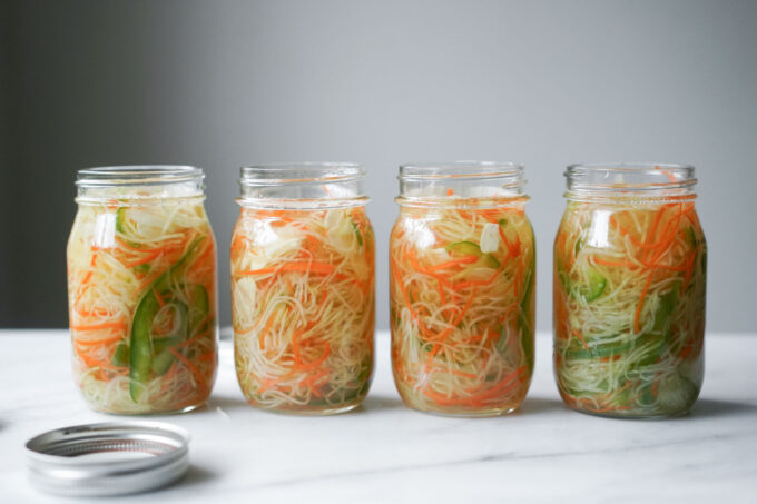 four glass jars filled with atchara