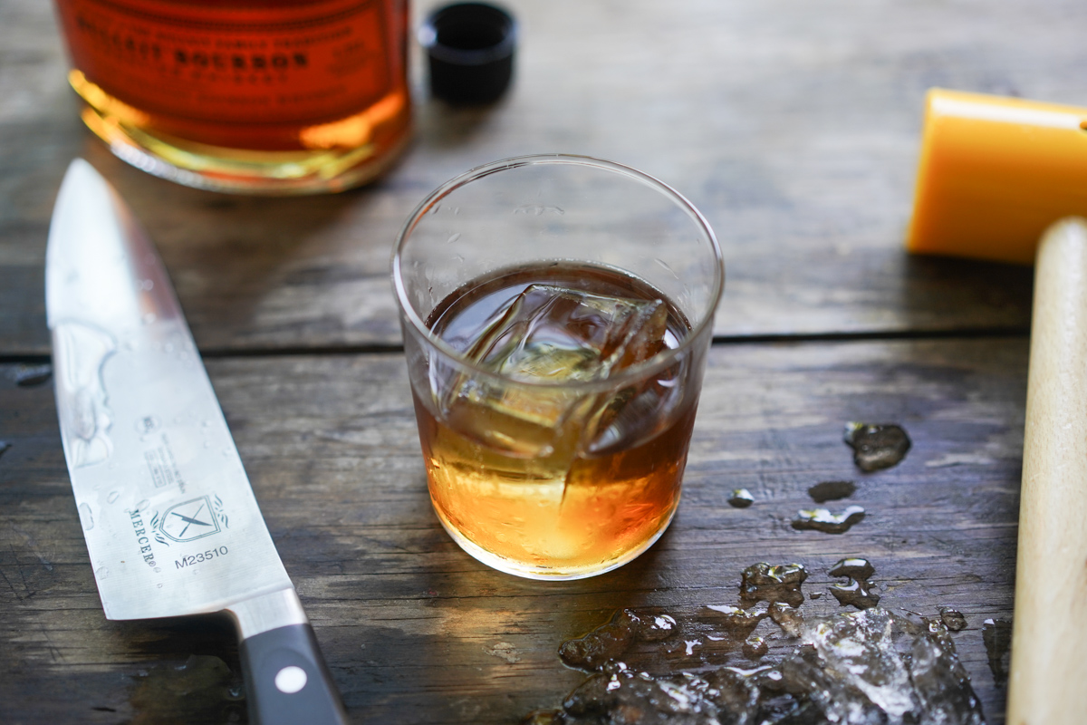 clear ice cube chilling a glass of bourbon