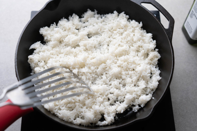 breaking up rice into small pieces in pan