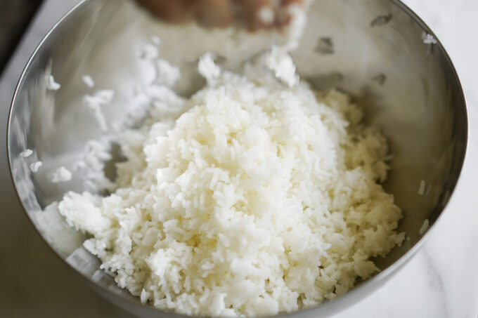 breaking up rice by hand into steel bowl