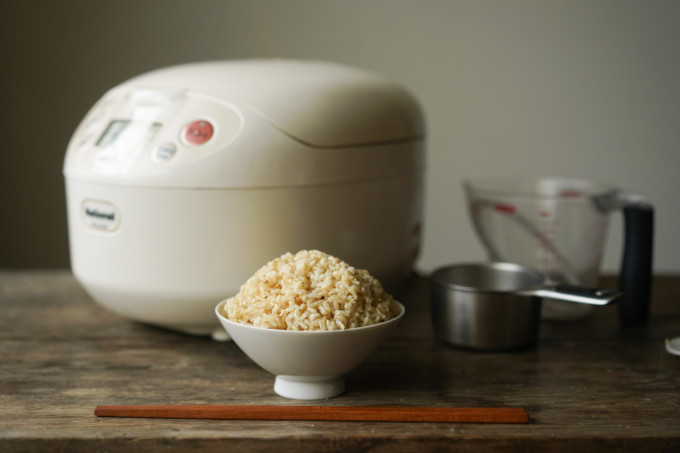 bowl of brown rice next to rice cooker