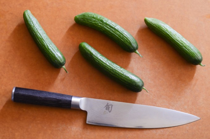 persian cucumbers and knife on a cutting board