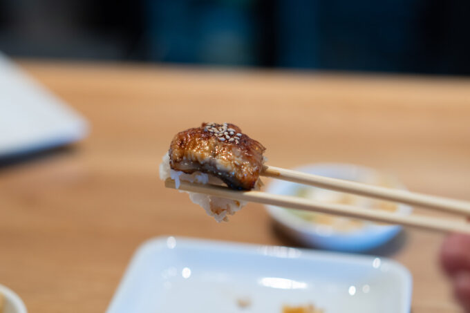 holding eel sushi with chopsticks
