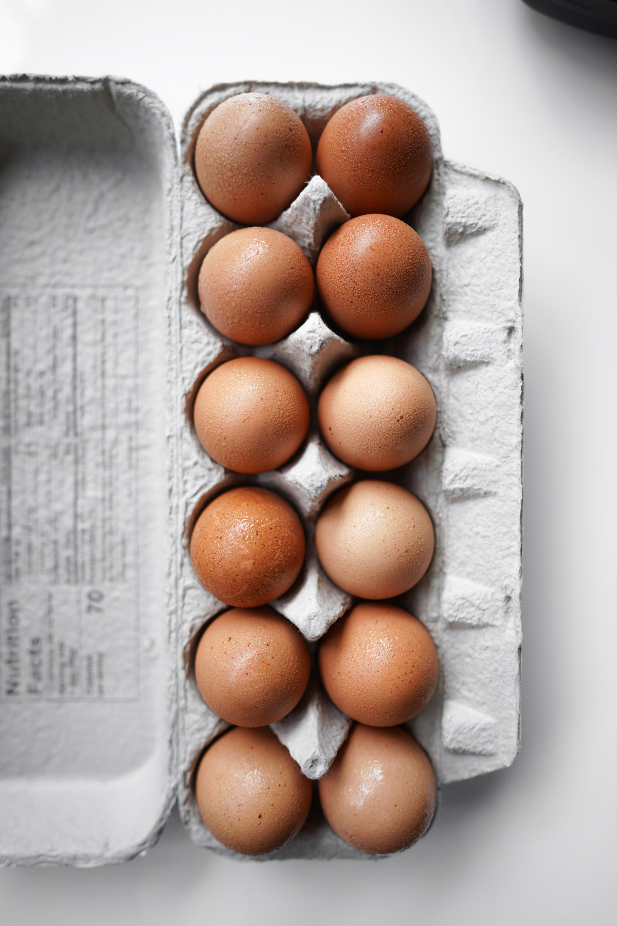 dozen eggs in a carton, with condensation