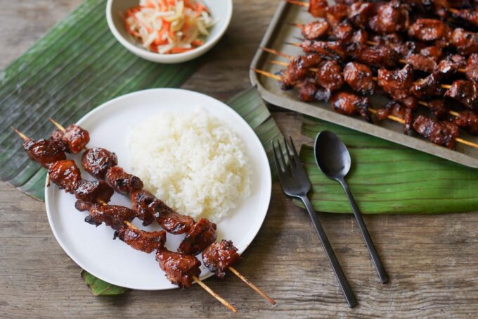 plate of rice, with bbq pork skewers, and Filipino pickles on the side