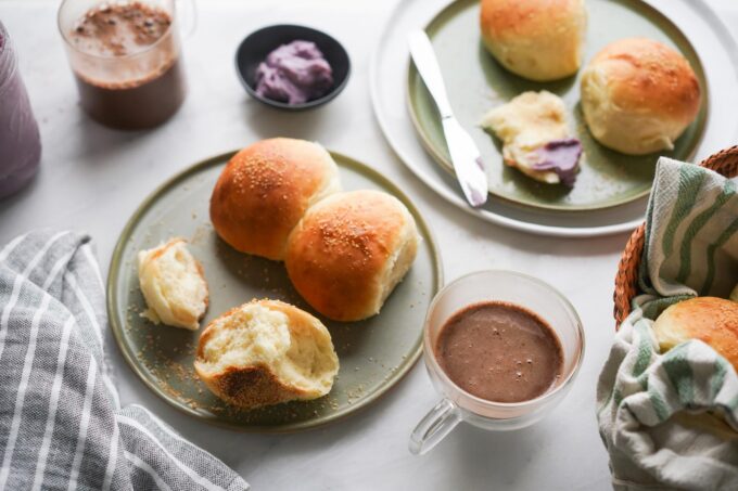 plates of pandesal with hot chocolate and ube halaya