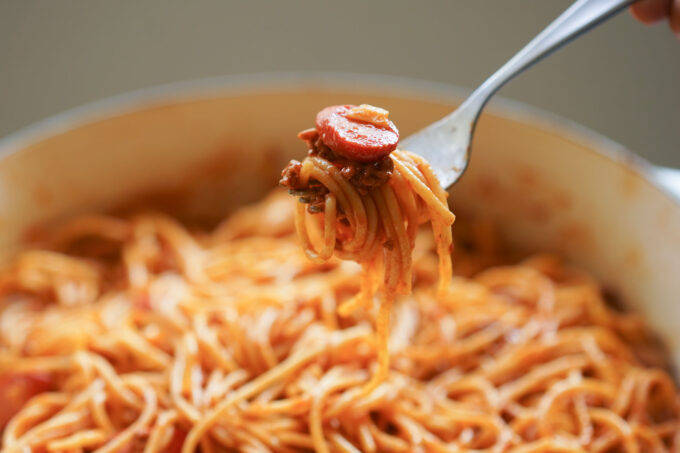 filipino spaghetti, with hot dog and cheese on a fork