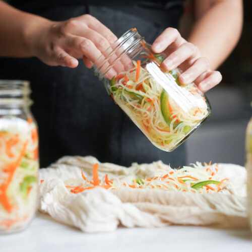 filling glass jars with atchara by hand