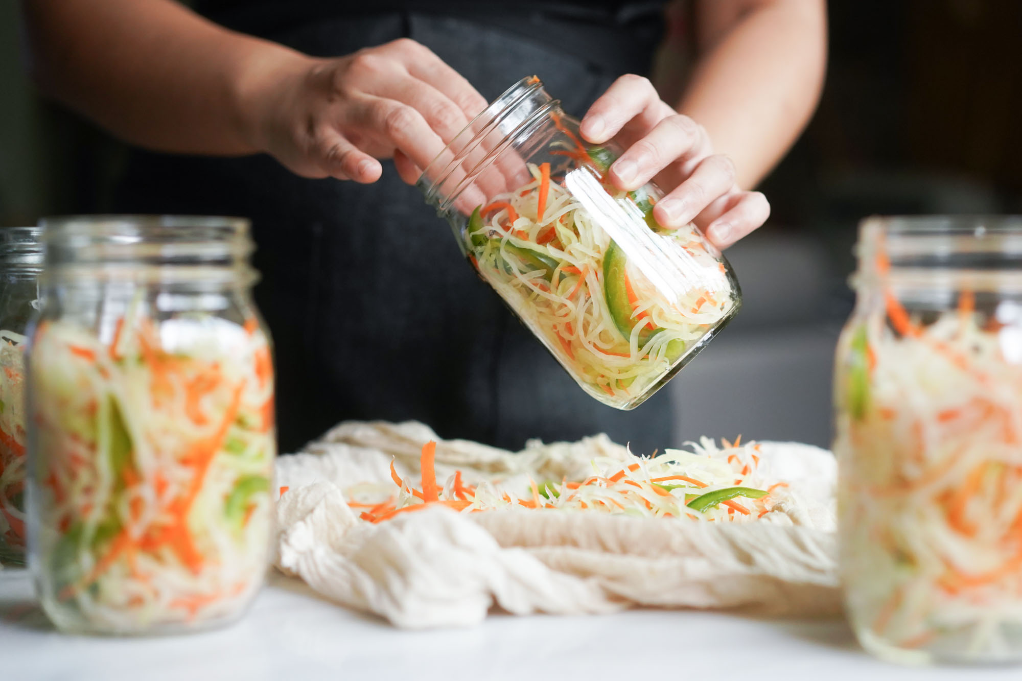 filling glass jars with atchara by hand