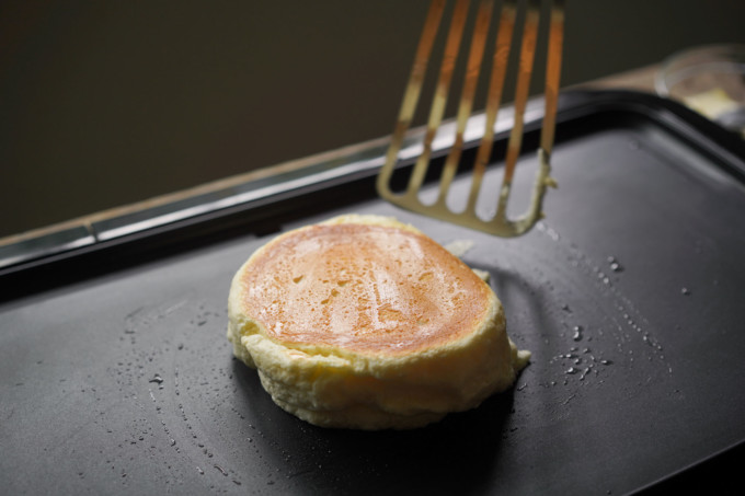 a flipped souffle pancake on a hot griddle