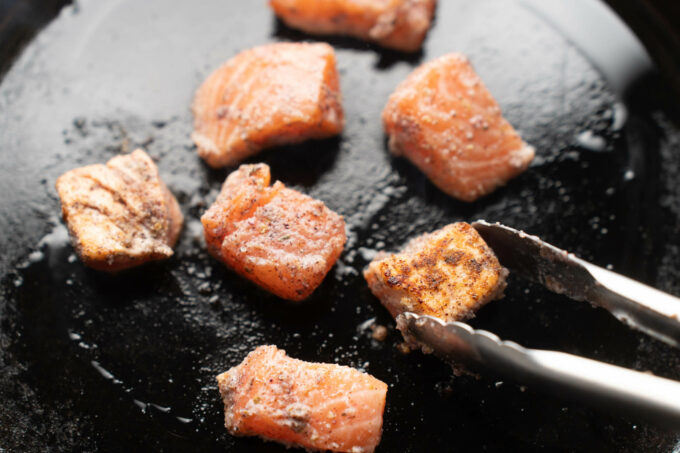 turning salmon cubes with tongs