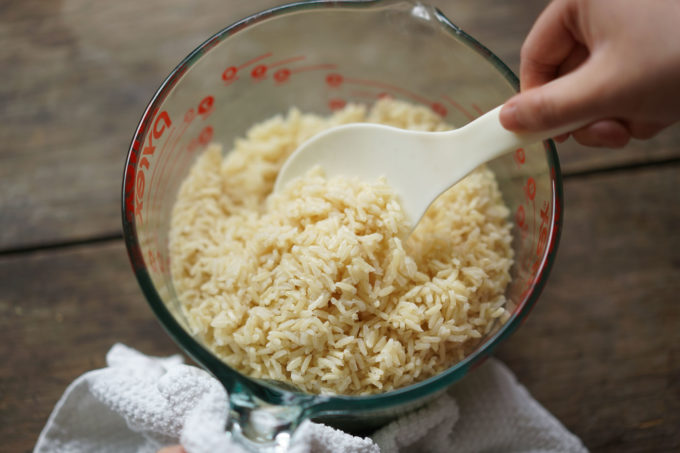 fluffing cooked rice with a paddle