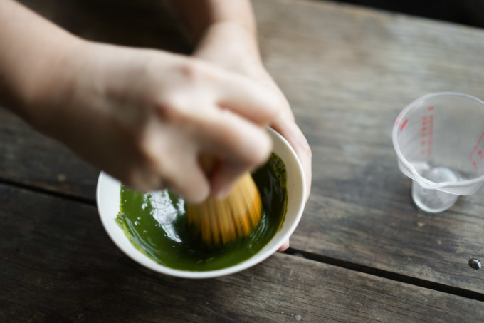 frothing matcha with a bamboo whisk