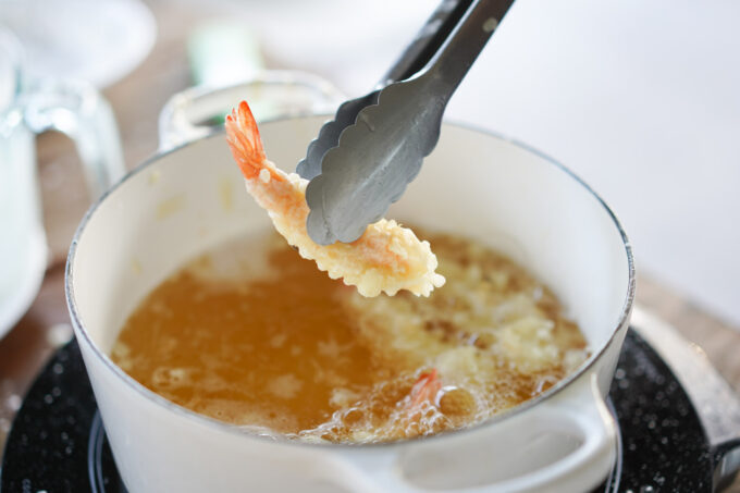 tongs holding a friend shrimp tempura