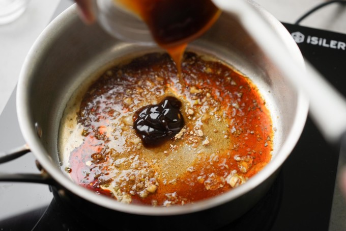adding oyster sauce ingredients to a pot