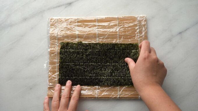 placing half sheet of nori on rolling mat