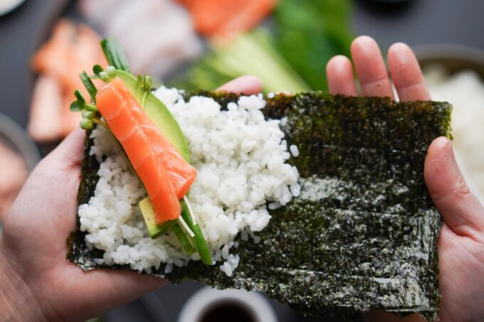 adding salmon and veggies to hand roll