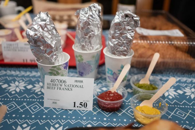Costco hotdogs wrapped in foil next to condiments