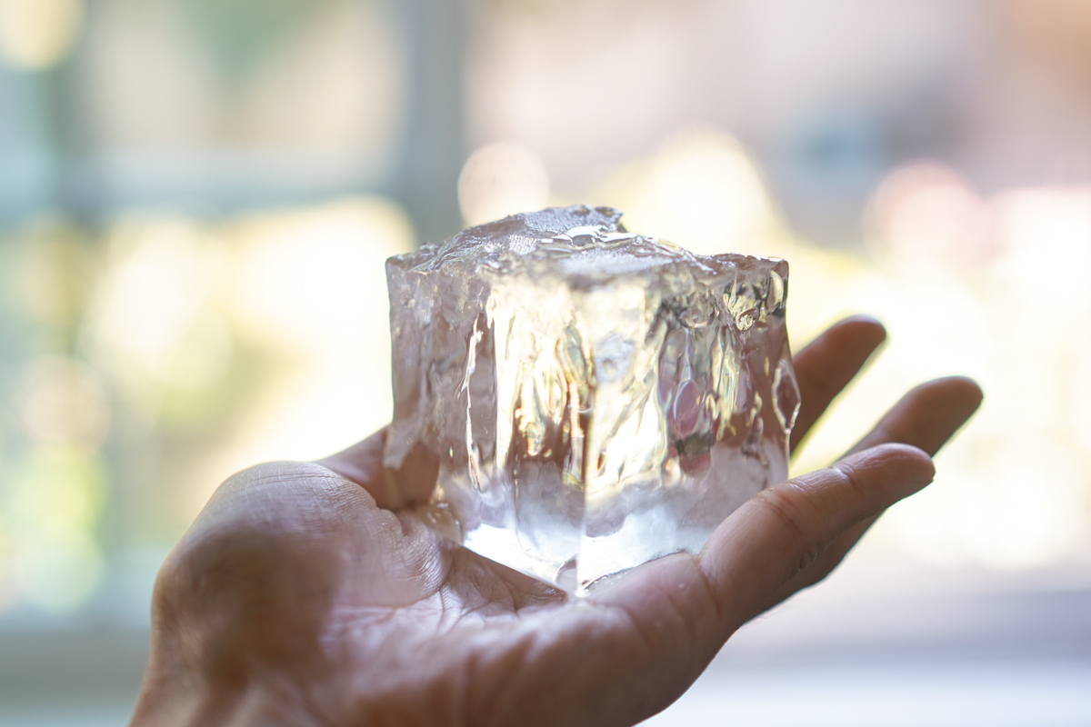 clear ice cube closeup in a hand