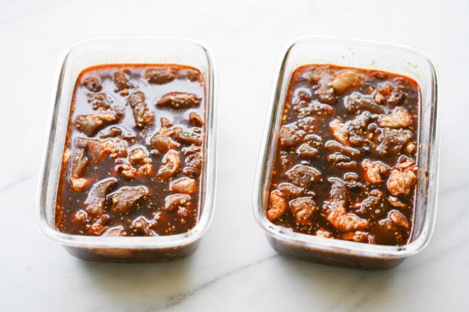 two glass containers with pork marinating in them