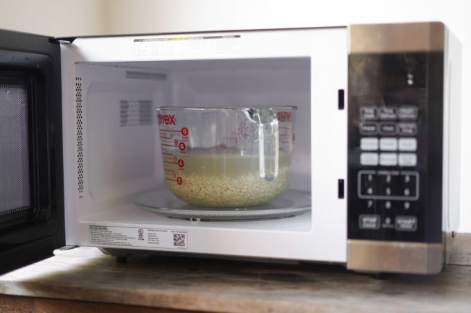 bowl of brown rice and water uncovered in microwave