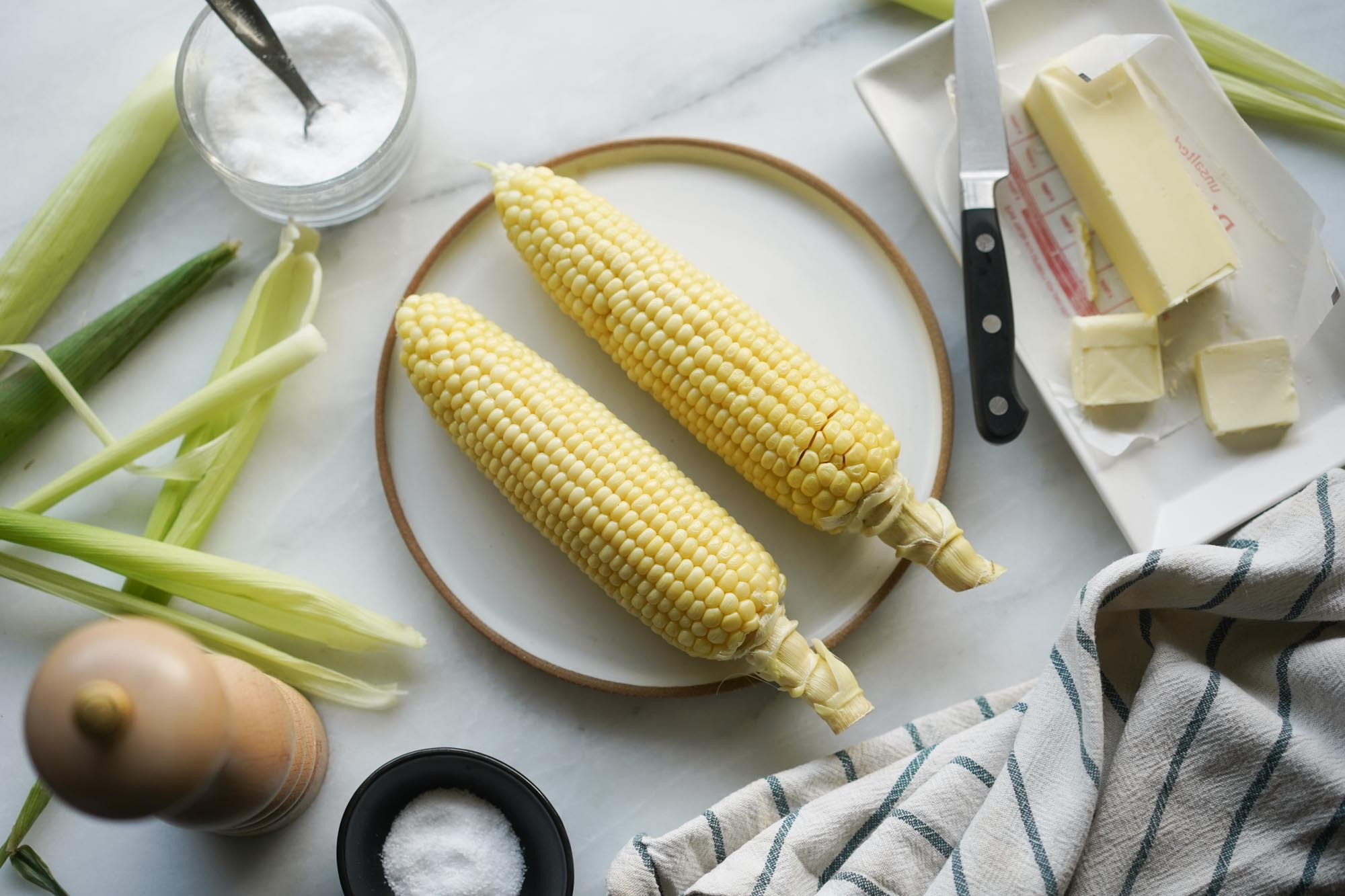 microwaved corn on a plate w butter, salt