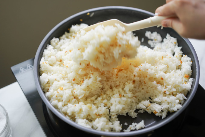 mixing rice with browned garlic in the pan