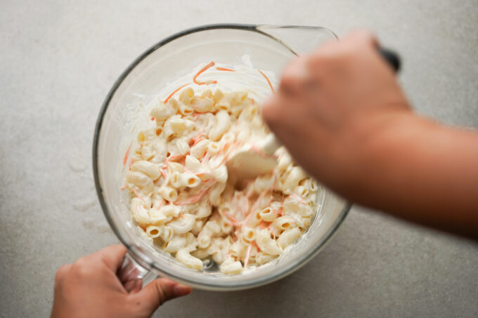 mixing macaroni into the dressing