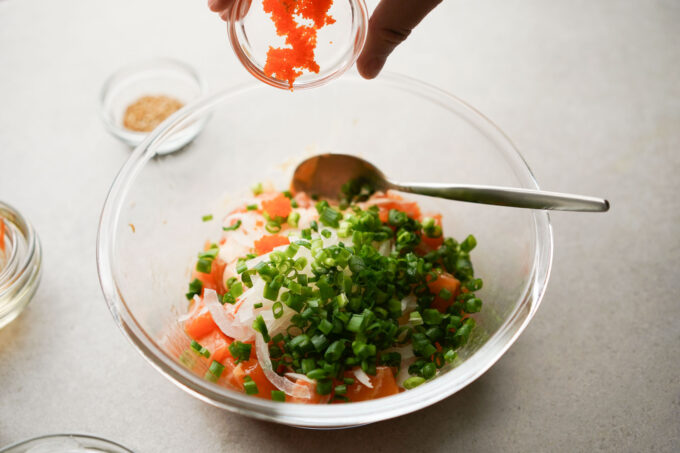 adding ingredients into salmon poke bowl