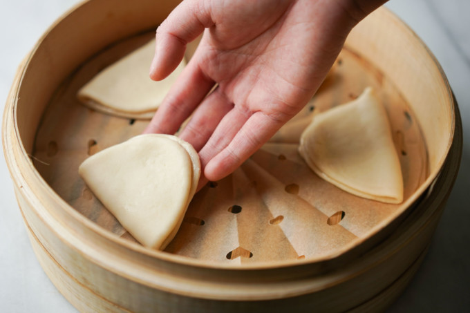 placing rolled bao in bamboo steamer