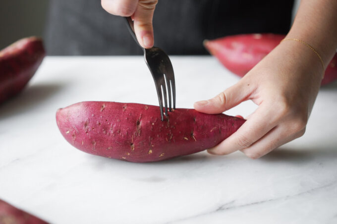 poking holes into the sweet potatoes