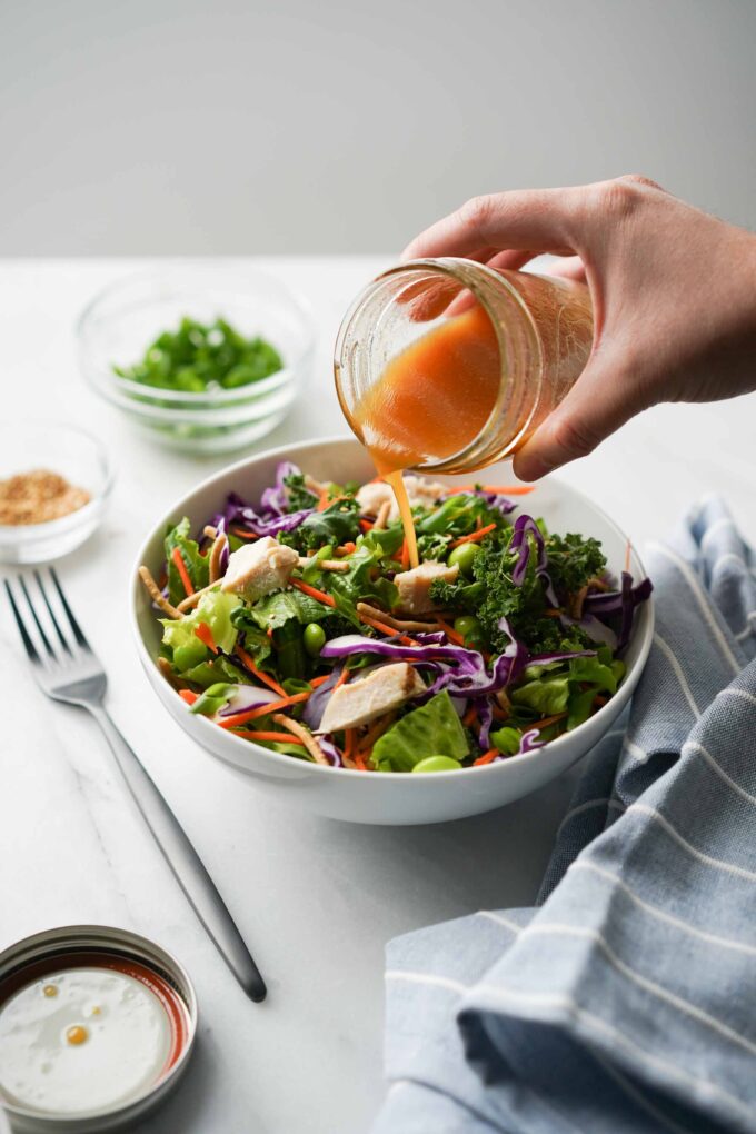 asian salad dressing poured on bowl of salad