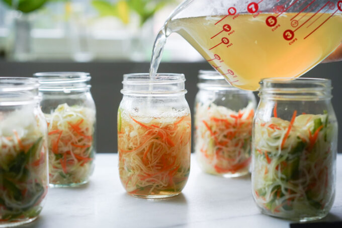 pouring the pickle brine into glass jars