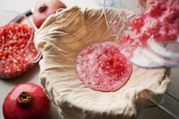 straining pomegranate puree with cheese cloth