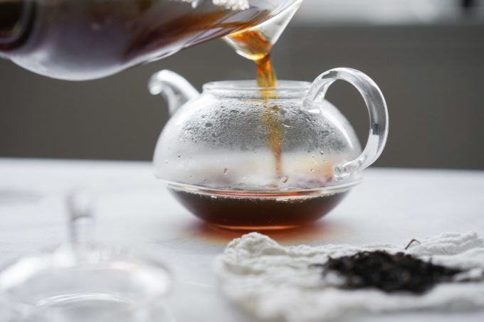 pouring brewed tea into a pot