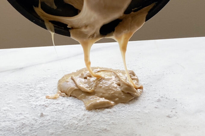 pouring out dough from pan onto a marble surface