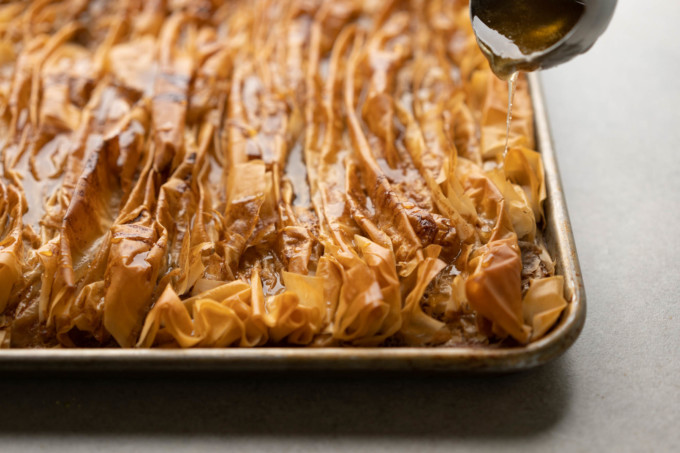 pouring simple syrup onto phyllo