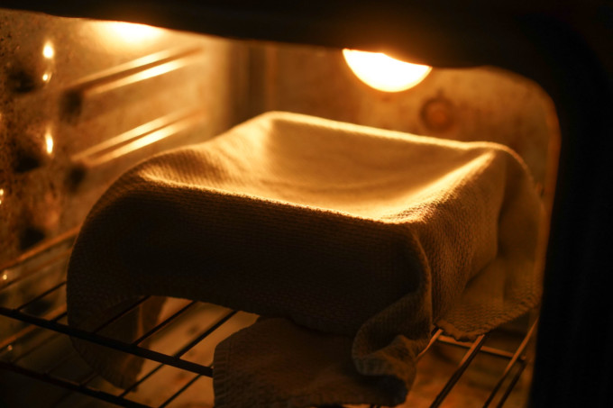 tray of dough covered with a towel in the oven to proof