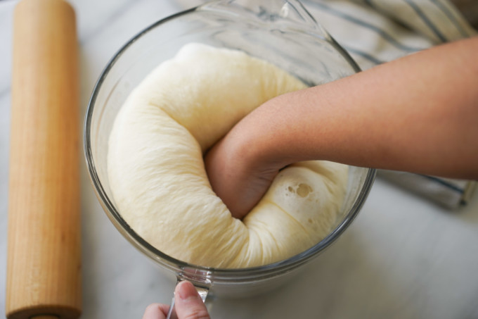 punching dough to remove gas
