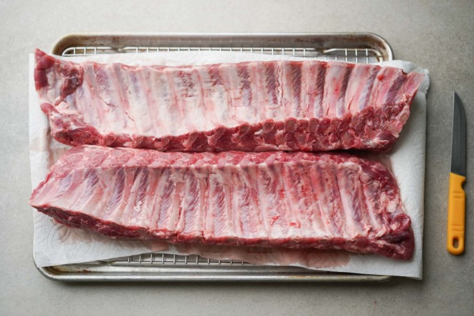 two raw racks of pork baby back ribs