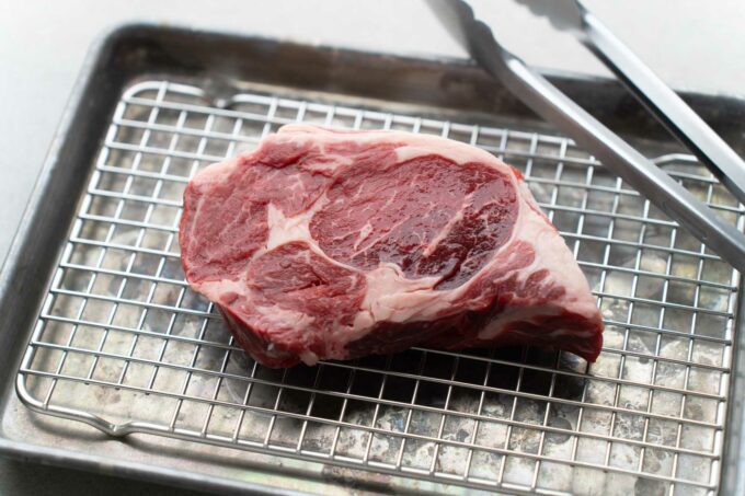 raw ribeye steak on cooling rack